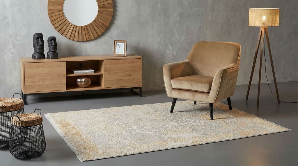 Ein moderner Wohnzimmer-Teppich in Beige und gold mit Vintage-Muster vor Sessel und Sideboard